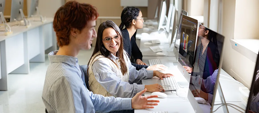 Étudiants qui discutent en regardant des écrans d'ordinateur
